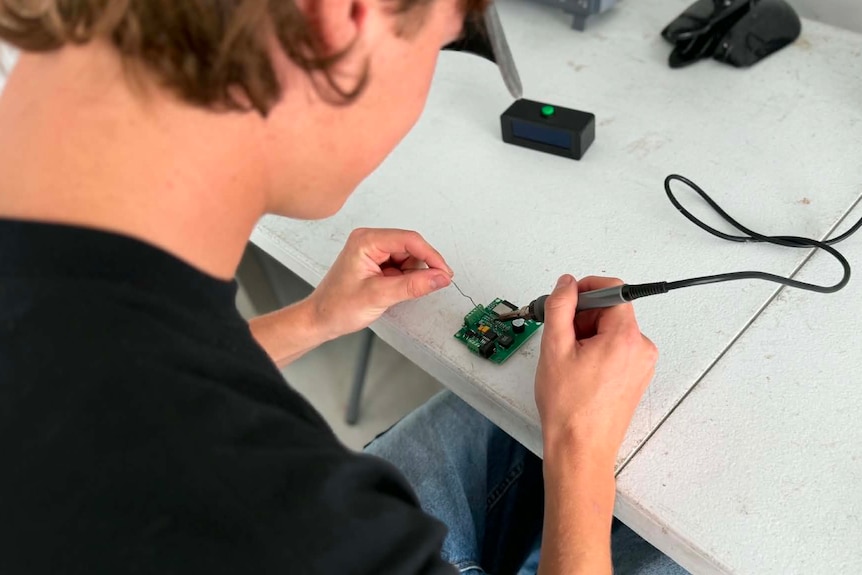Man with hands working on electrical board