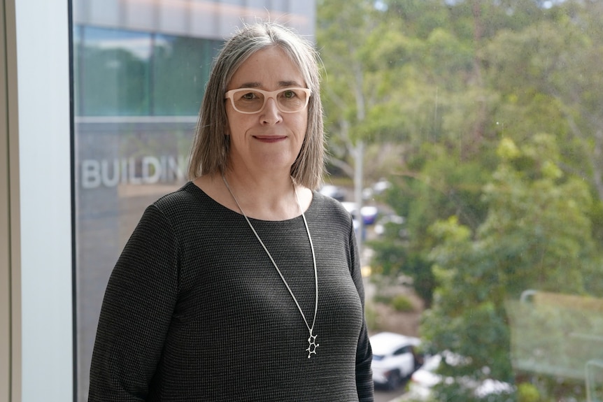 A woman wearing glasses smiling.