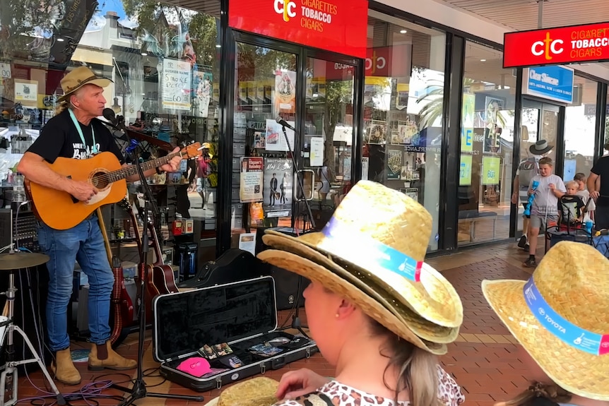 A man busking in front of a shop before a crowd