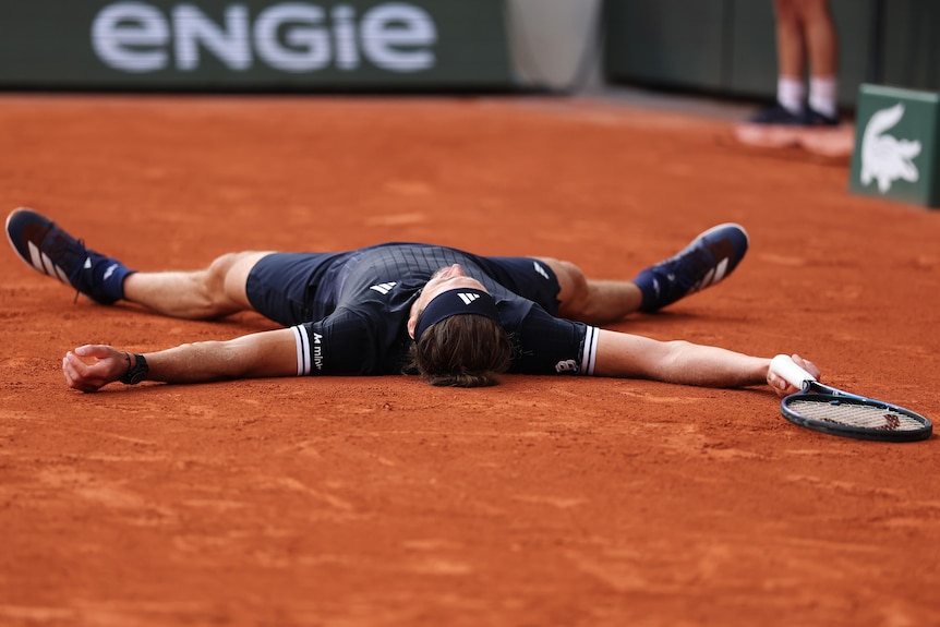 Alexander Zverev lies on the roland-Garros centre court.