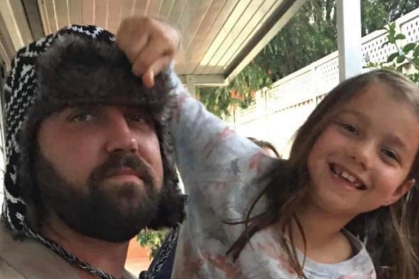 A man wearing a beanie, looking serious, with a smiling 10-year-old girl.