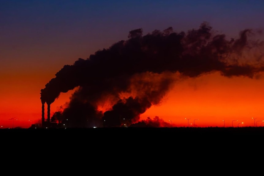 A sunset photo showing steam stacks in silhouette.