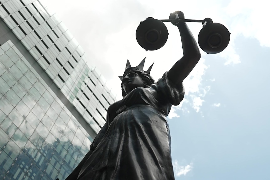 A close-up of the lady justice statue with blue sky above.