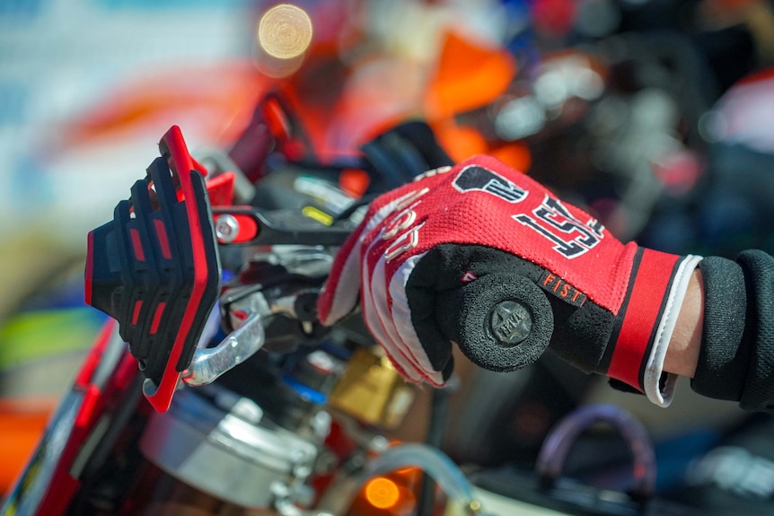 A close-up of gloved hands squeezing the brakes on a motorbike.