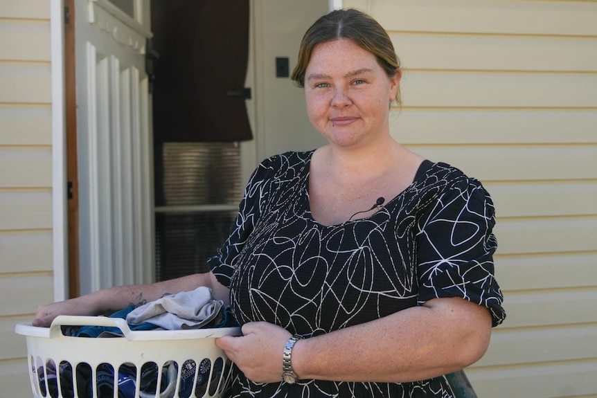 young woman in a black dress holding a basket of laundry.
