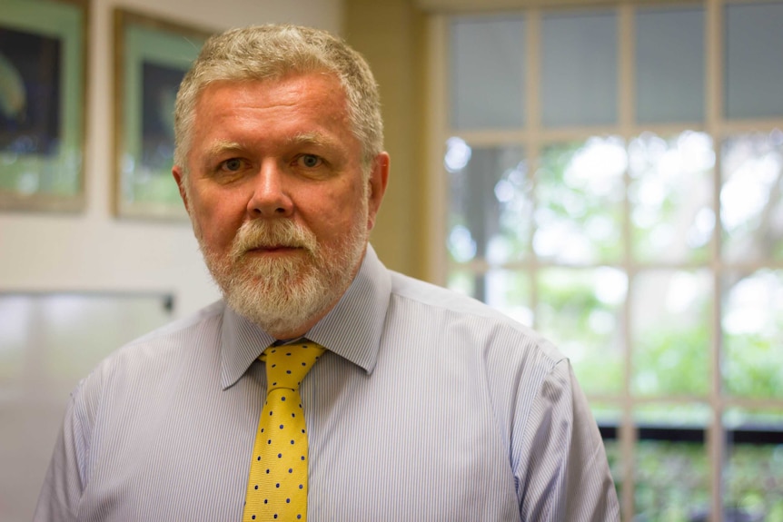 A man in a business shirt and a bright yellow tie.