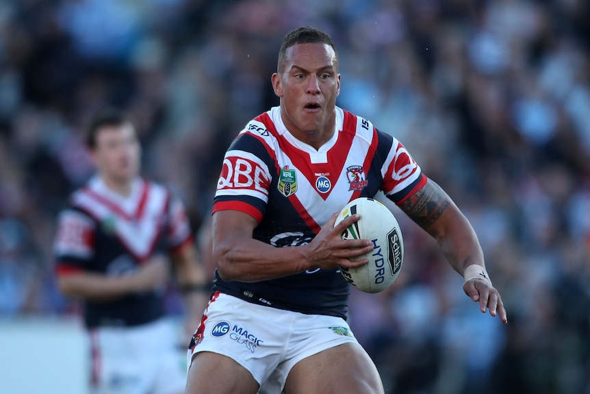 A man runs the ball during a rugby league match.