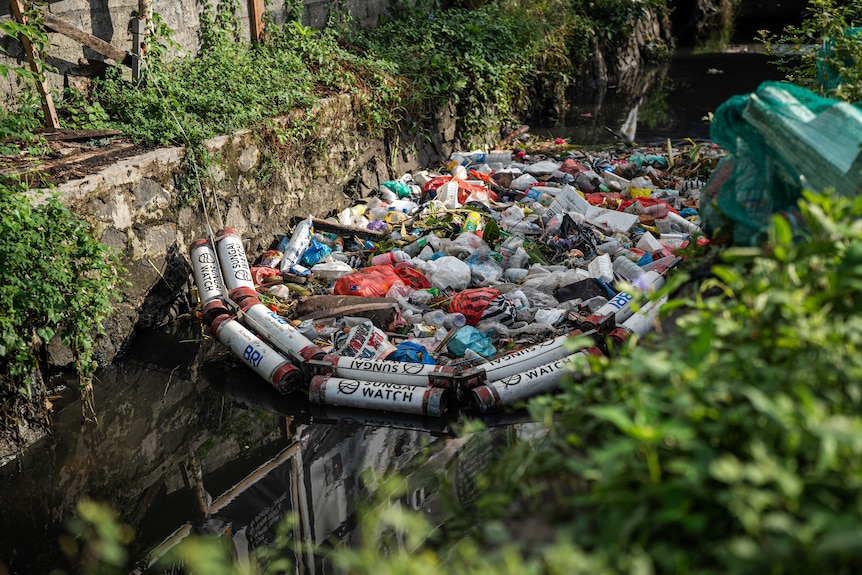 A trash barrier prevents rubbish from filtering downstream in a river in Bali's Denpasar.