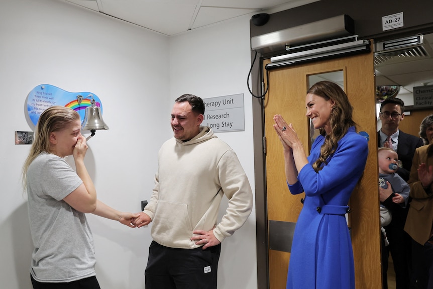 Princess Kate clapping as a cancer patient rings the end of treatment bell with her husband next to her