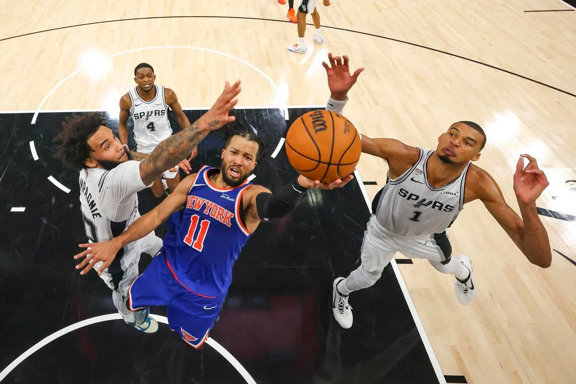 New York Knicks guard Jalen Brunson drives to the basket past San Antonio Spurs forwards Julian Champagnie and Victor Wembanyama during Game 2 of the NBA Finals.