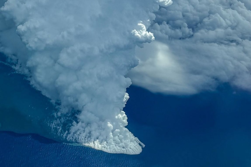 A cloud of white smoke steams up from under a deep blue ocean
