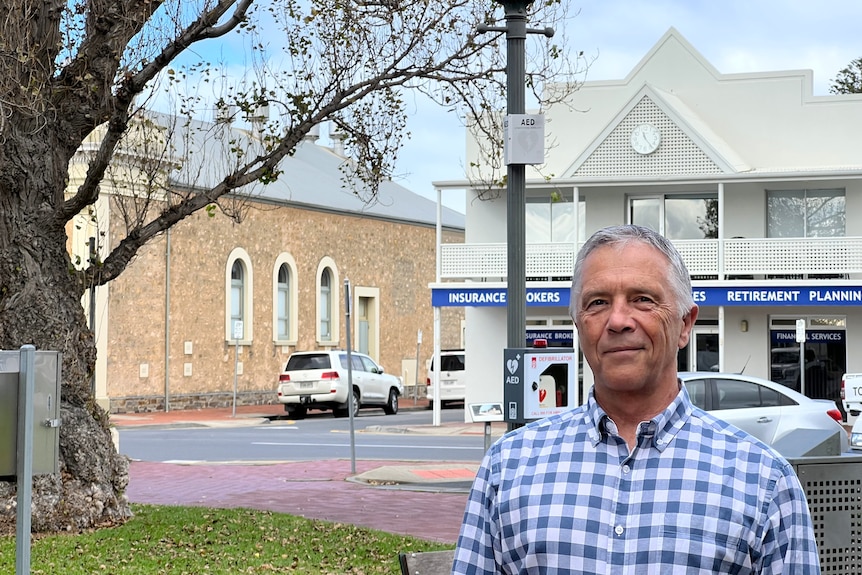 A man stands in a park with offices and a historic building behind him