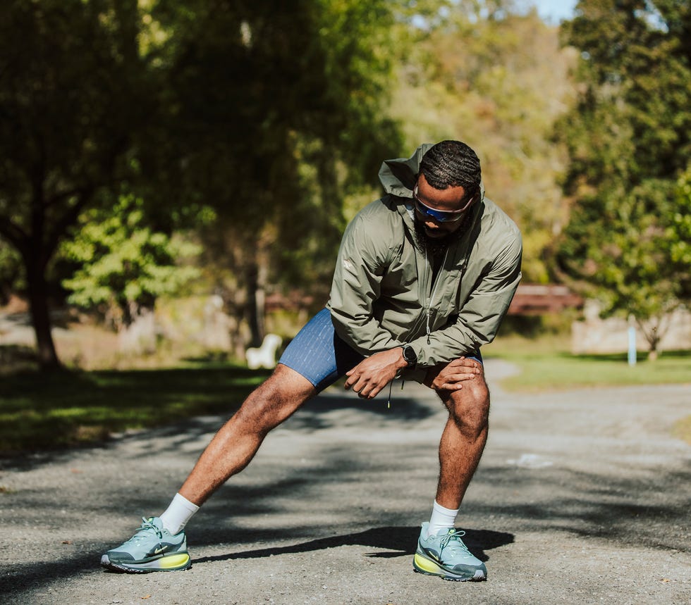 Individual stretching on a gravel path in a park.