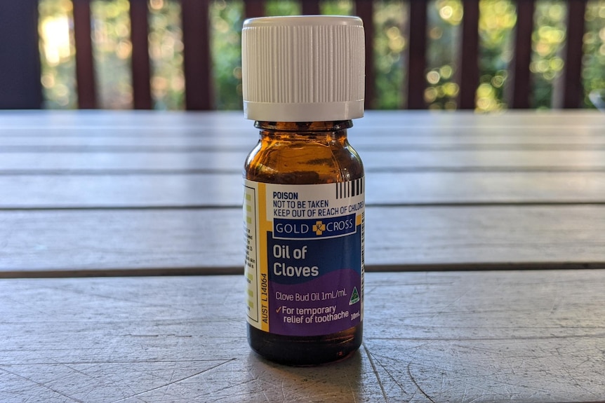 A small bottle of clove oil on an outdoor table.