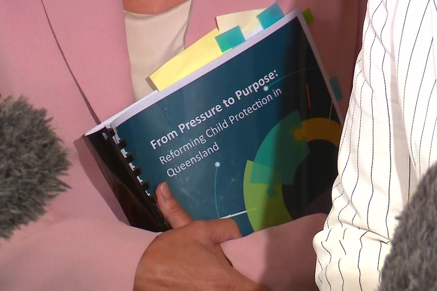 A report being held by a person in a pink top