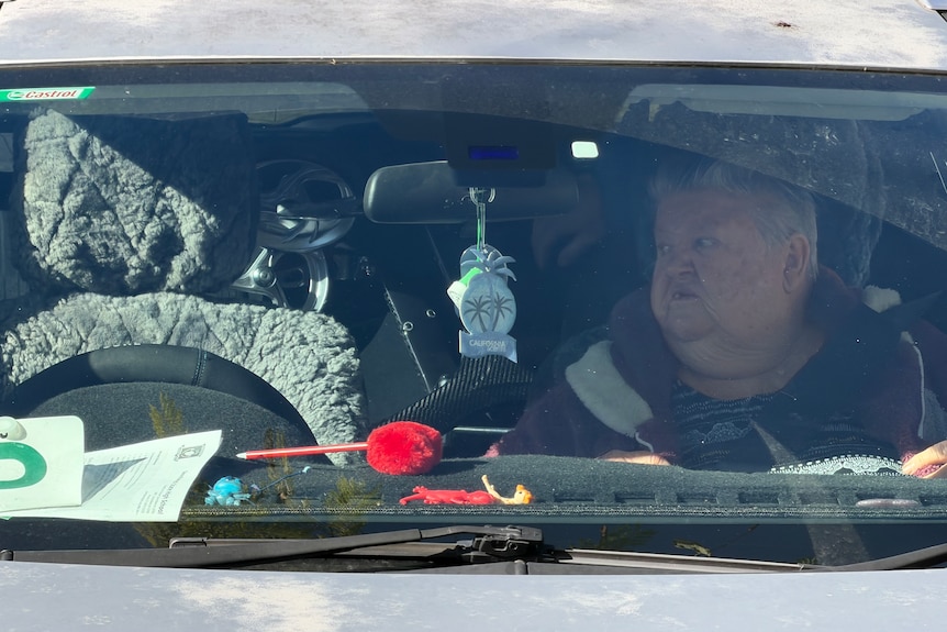 A woman with short hair is sitting in a car.