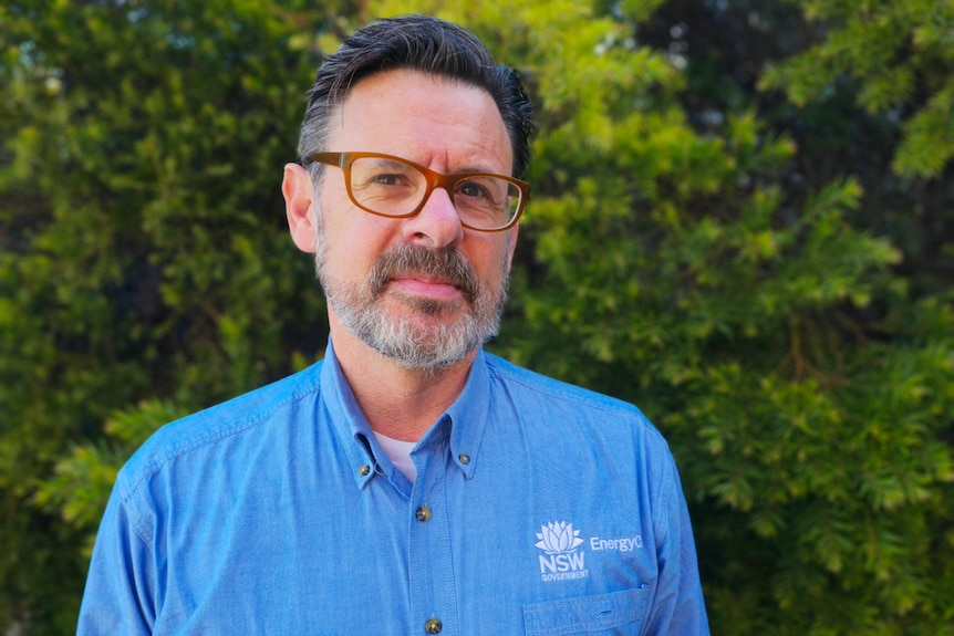 A man in glasses and a bright blue shirt labelled EnergyCo