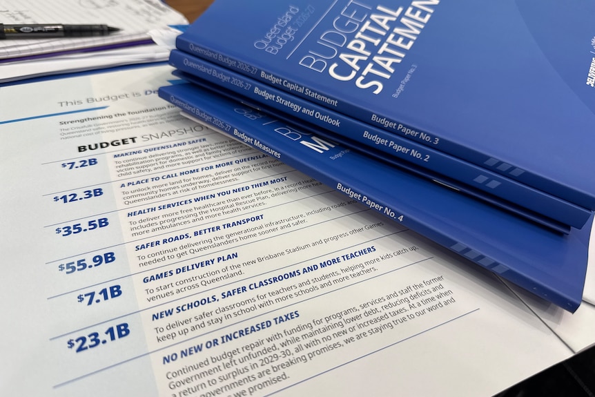 Blue book and white budget papers on a table.