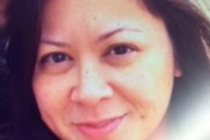 A close-up of a woman with long, dark hair. She is smiling.