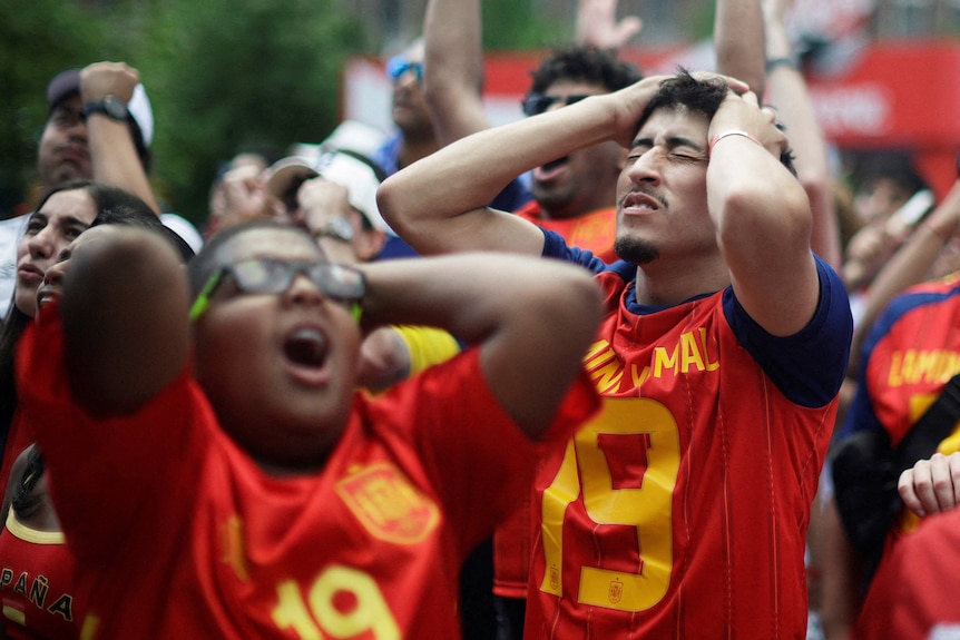 spanish fans with hands to their heads upset