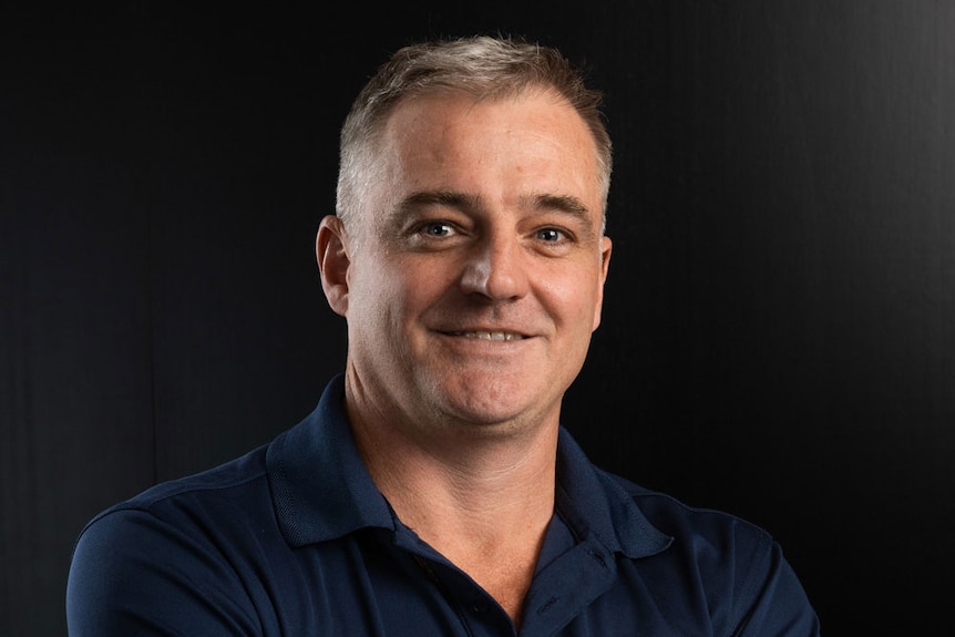 A man in a tshirt smiles at the camera