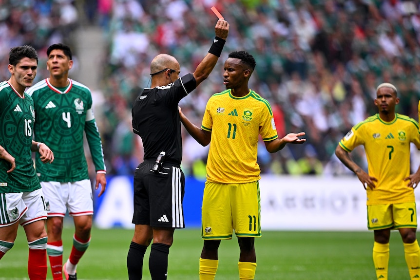 Themba Zwane holds his hands out as the referee shows him a red card