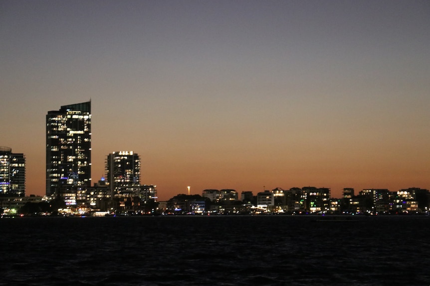 Lights going on in buildings after the sun has set.