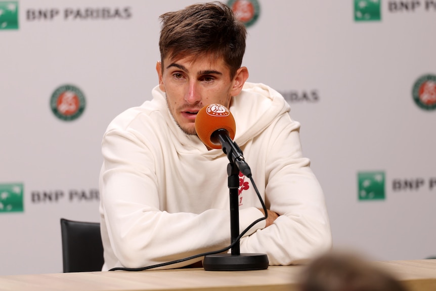  Matteo Arnaldi speaks into a microphone at a media conference after withdrawing from the French Open.
