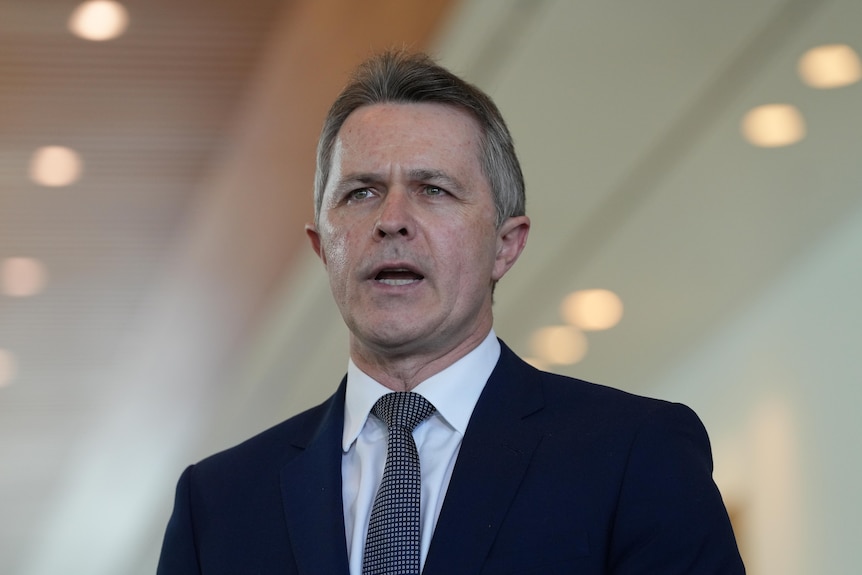 A close up of a man wearing a suit speaking.
