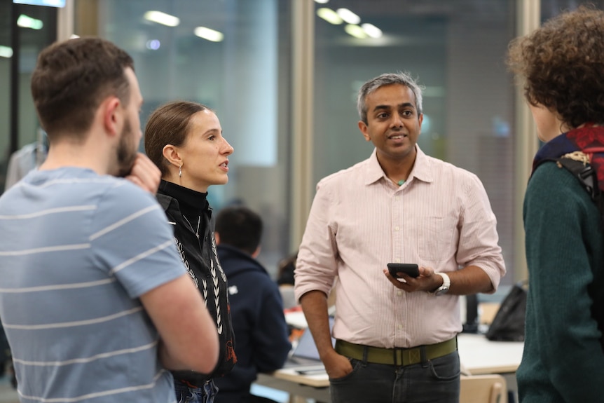 A man and woman standing next to each other talking to two other people