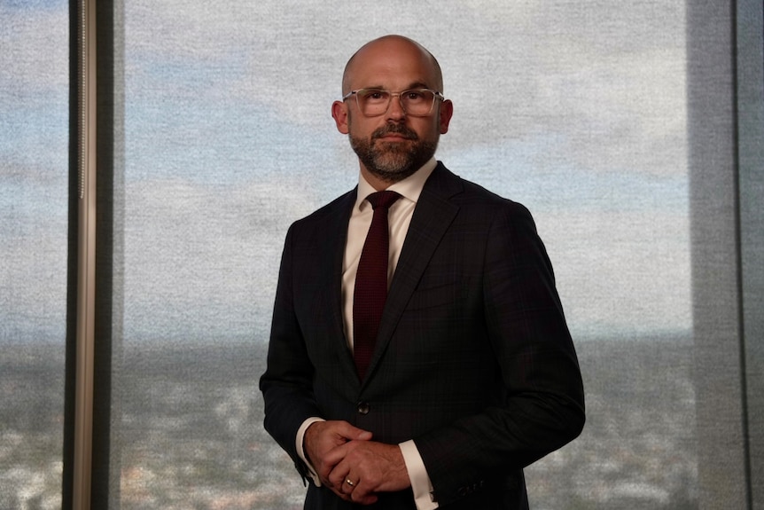 David Janetzki wearing a suit and glasses looks into the camera
