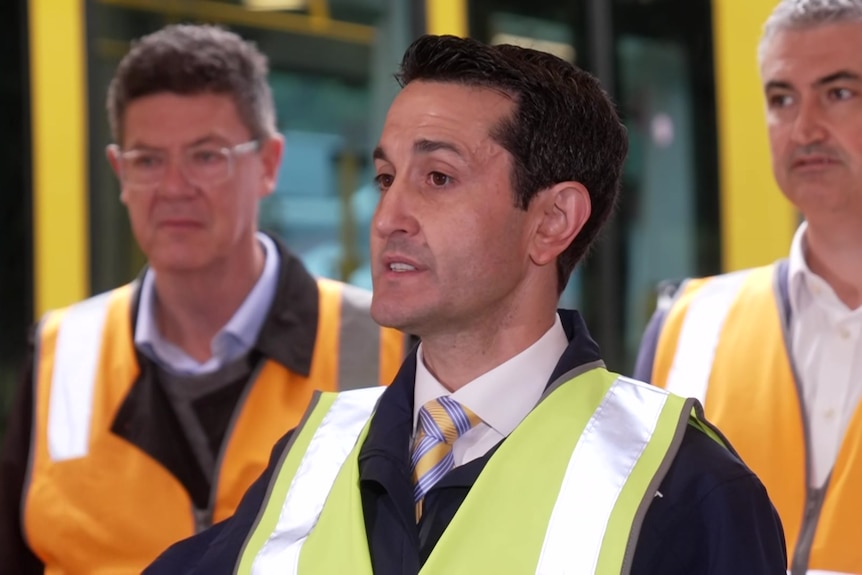 Queensland premier wearing a high-viz vest at a press conference.