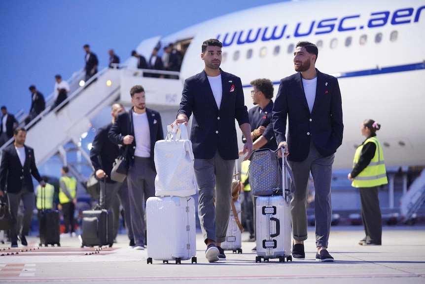 Iran's Mehdi Taremi and Alireza Jahanbakhsh walk away from a plane in Tijuana
