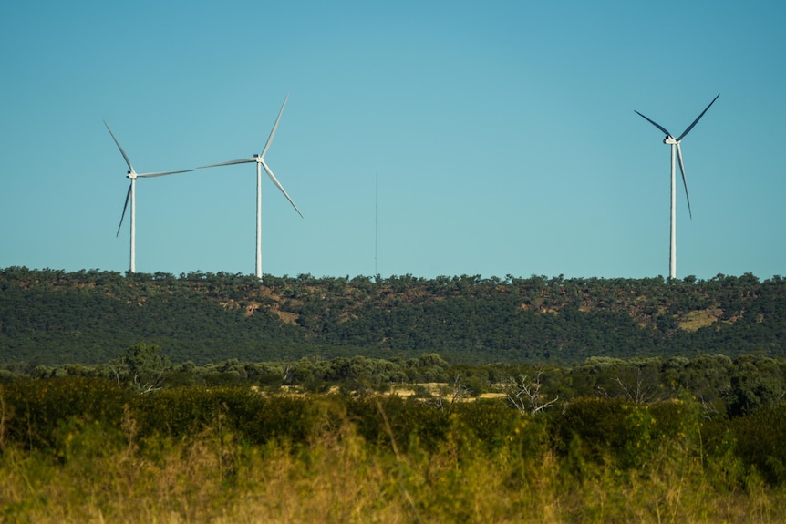 Three wind turbines on a green hill
