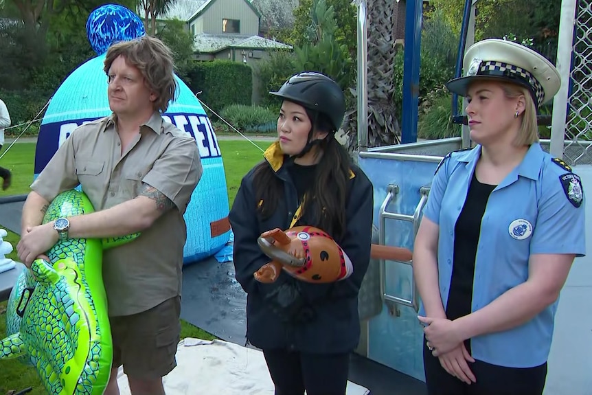 A man dressed as Steve Irwin with a blow-up crocodile a woman with a hobby horse and helmet and a woman dressed as a cop.