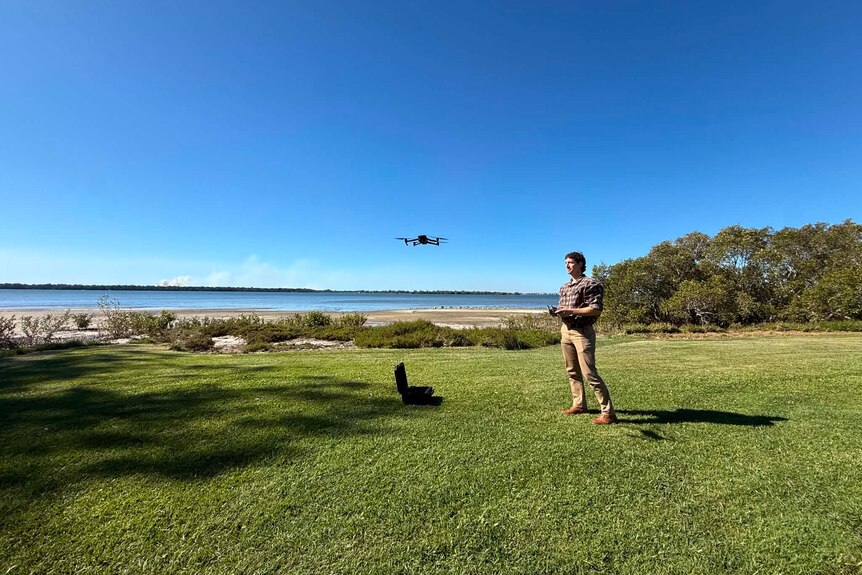 Man operating drone at shoreline