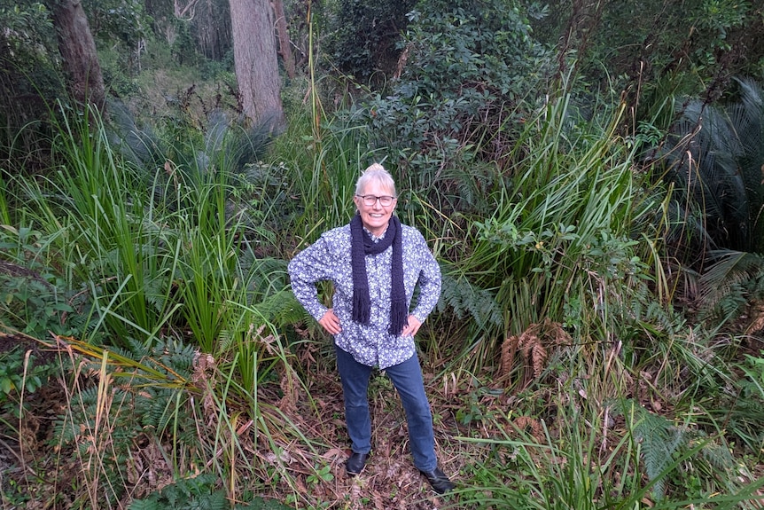 A woman stands in bushland, looking up at the camera
