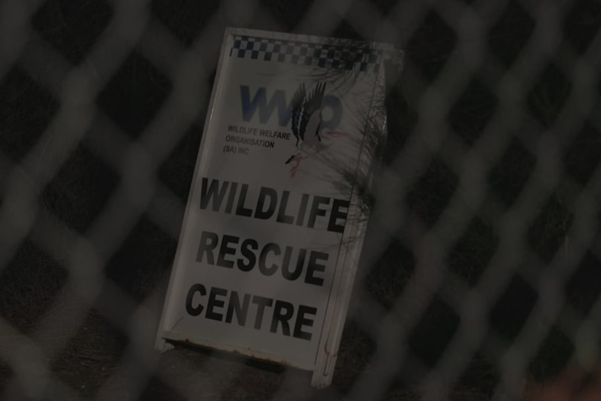 A white sign with the words 'Wildlife Rescue Centre' on it photographed through a wire fence