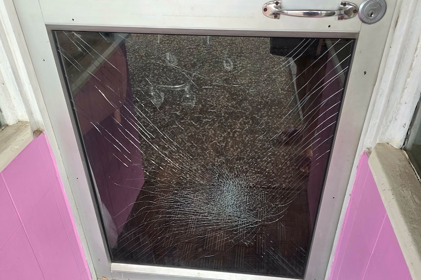 Broken glass surrounds the entrance to a Mount Isa business after a glass door was smashed during a vandalism incident.