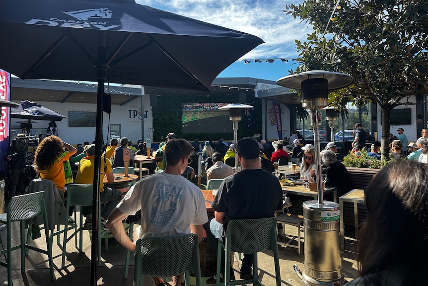 Group watching game outside with man in cap salient 
