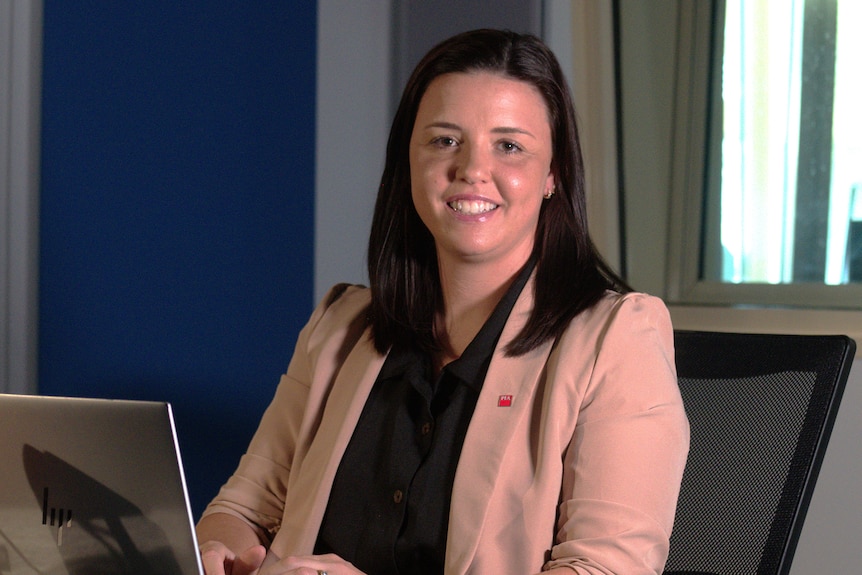 A woman working on a computer smiling at the camera.