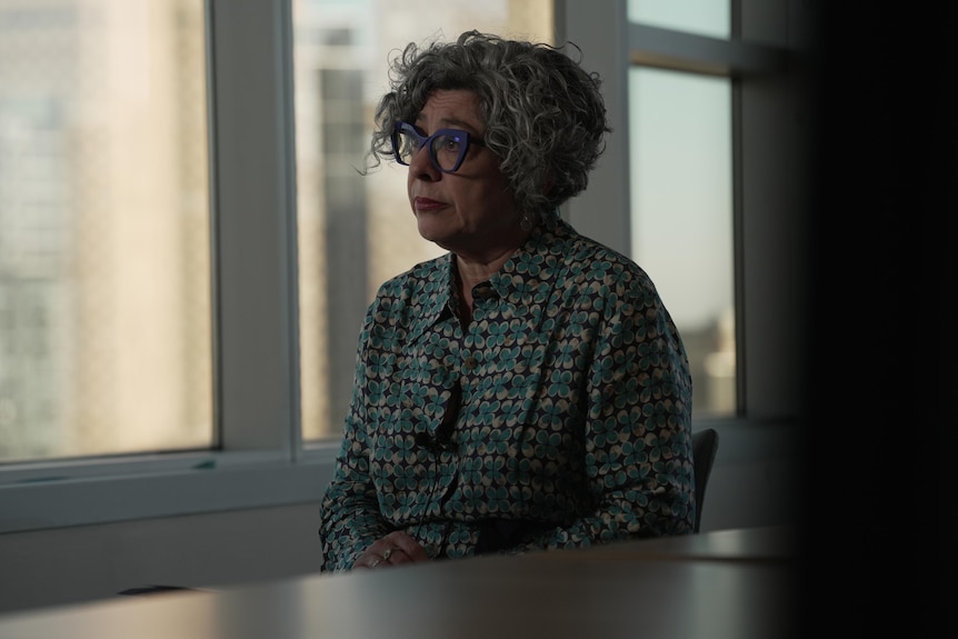 A woman with blue glasses sitting near a table
