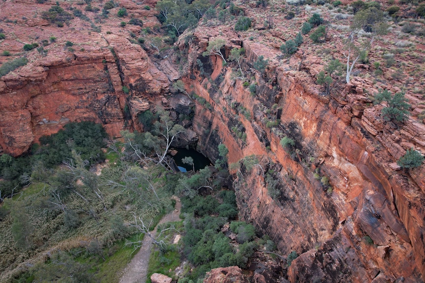 A view through a red rock canyon to a waterhole.