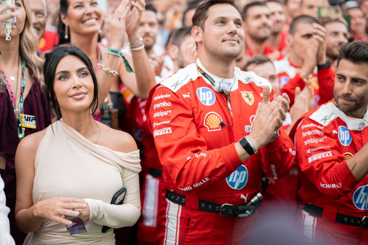 Kim K smiling in the crowd beneath Monaco podium next to Ferrari team members