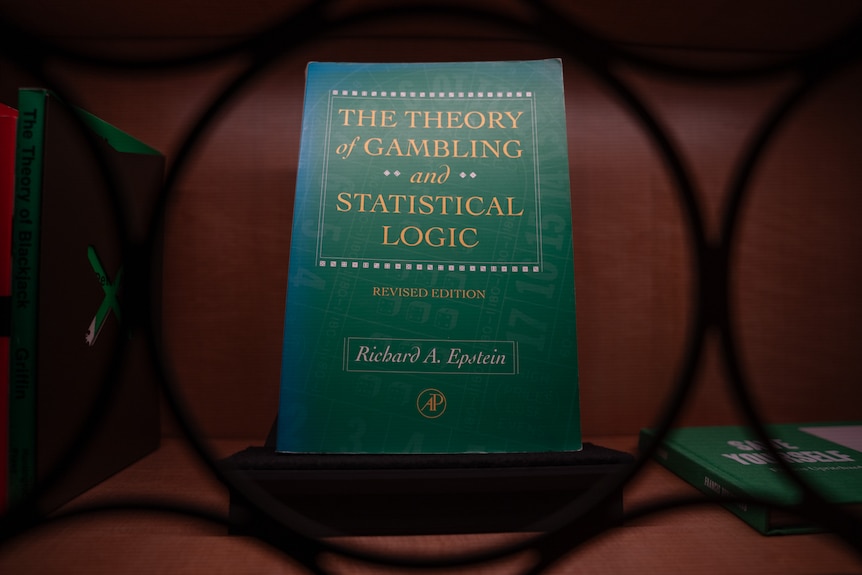 A book, The Theory of Gambling and Statistical Logic, sits behind a locked cabinet.