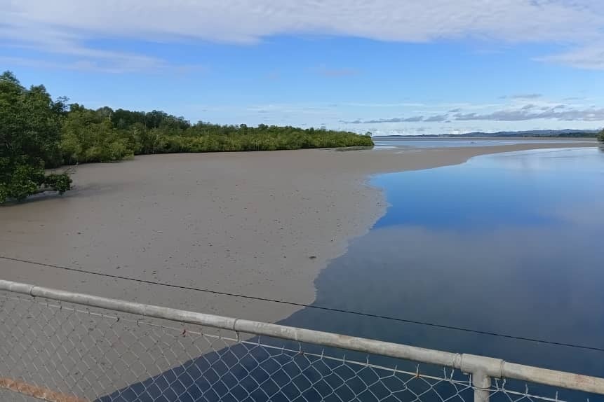 A brown streak sits on the water lapping the coastline and stretching out into the distance