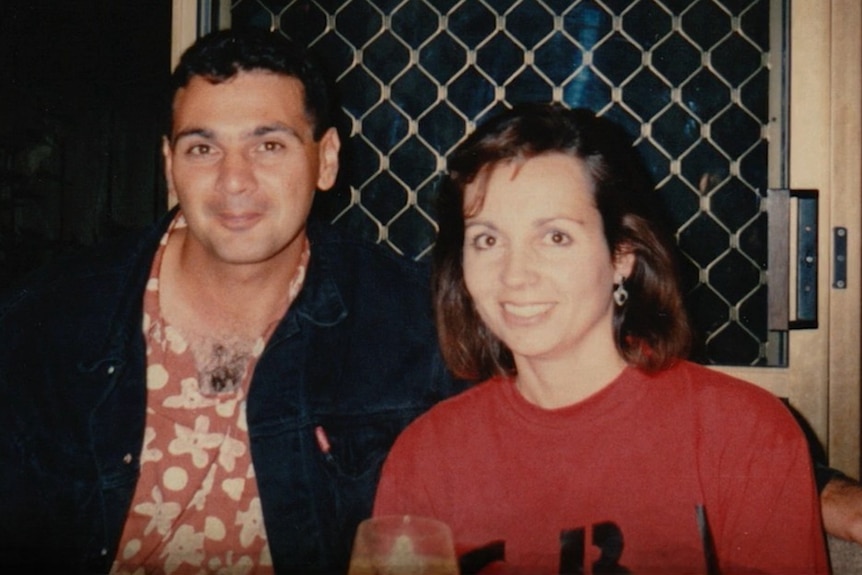 An old photo of a woman in a red shirt sitting next to a man with a black coat on