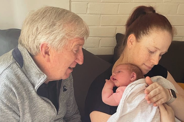 Erin sitting next to her dad and holding her young daughter close to her chest.