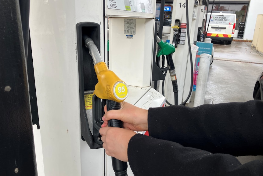 Two hands on a premium petrol pump.