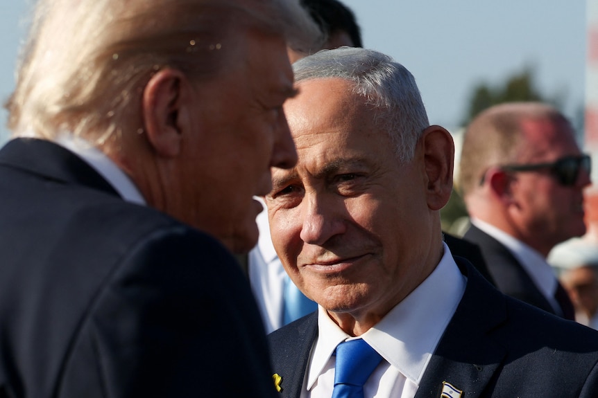 Benjamin Netanyahu looks on next to Donald Trump.